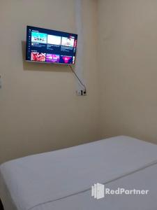 北加浪岸Navisha Guest House Syariah near Exit Tol Batang RedPartner的床上方的墙上设有平面电视