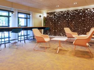 佩皮尼昂佩皮尼昂中心美居酒店的一间设有椅子和桌子的等候室,以及一堵带圆点的墙壁