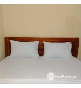 北加浪岸Navisha Guest House Syariah near Exit Tol Batang RedPartner的一张带两个白色枕头和木制床头板的床