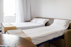 邦比尼亚斯Makkai Resort Bombinhas的带窗户的客房内的两张床