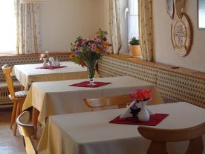 拉姆绍达赫斯坦贾格豪索尔酒店的餐厅里有两个桌子,上面有鲜花