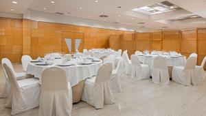 雷阿尔城NH皇城酒店的宴会厅配有白色的桌子和白色的椅子