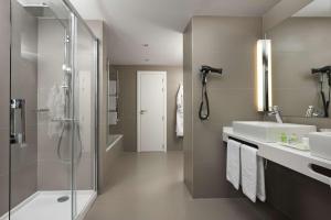 潘普洛纳NH潘普洛纳伊鲁纳公园酒店的一间带两个水槽和玻璃淋浴间的浴室