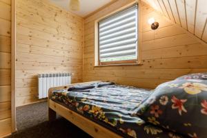 韦特利纳Bieszczadzka Ostoja的木制客房内的一间卧室,配有一张床