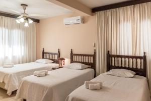 亚松森Paramanta Lifestyle Hotel的一间卧室配有两张带白色床单的床