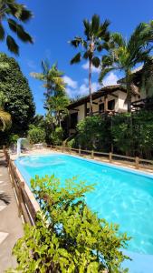 巴拉格兰德Taipabas Hotel的一座种植了棕榈树的蓝色游泳池和一座房子