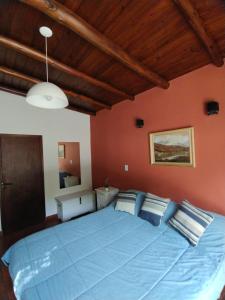 圣萨尔瓦多德朱CampoMora- 5 min del Centro - CONFORT - Parrilla & Pileta的卧室里一张大蓝色的床,卧室里设有红色的墙壁