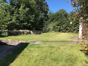 布雷肯Cobblers Cottage in Brecon Beacons的草地庭院,有石墙和树木