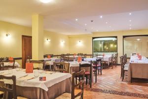 布伦托尼科Hotel Dolomiti的餐厅配有桌椅和白色的桌布
