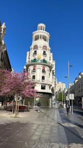 马德里DELUXE APARTMENT NEAR GRAN VIA的一座高大的白色建筑,前面有一棵开花的树