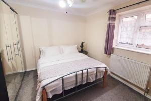 斯劳1 Bedroom Apartment close to Slough Train Station的一间卧室配有一张带白色床单的床和一扇窗户。