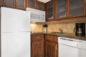 俄克拉何马城俄克拉何马市鹌鹑泉驻桥套房酒店的厨房配有白色冰箱和木制橱柜。