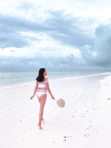 江比阿Sharazad Oasis Retreat的一名妇女站在海滩上,手里拿着球拍