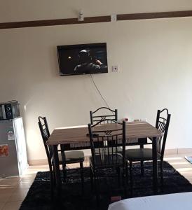 姆特瓦帕Mkombodzi Global Homes的餐桌、椅子和墙上的电视