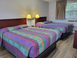 科堡Knights Inn Cobourg的酒店客房设有两张床和窗户。