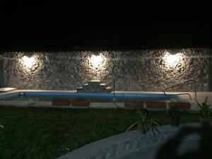 卡法亚特Hostal Candelaria的一座晚上在石墙上点亮灯的游泳池