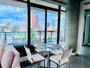 卡尔加里LUXURY DT, 2 Bedroom DEAL, Private Balcony, Full Kitchen, Gym - FREE PARKING的配有大窗户的客房内的桌椅