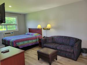 科堡Knights Inn Cobourg的客厅配有沙发、一张床和椅子
