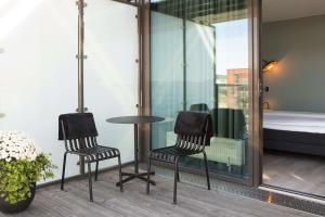 奥斯陆斯福尔斯堪迪克酒店的阳台配有两把椅子和一张桌子,阳台配有床