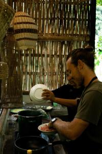 塔巴南Bali Jungle Camping by Amerta Experience的在一个厨房里准备一盘食物的人