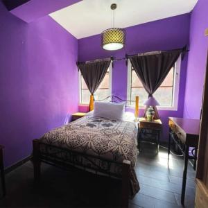 瓜纳华托Casa Jardín的一间紫色卧室,配有一张床和一架钢琴