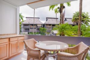 希洛Waiakea Villas 2-207的一个带桌椅的阳台和一座建筑