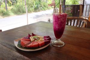 珀尼达岛Misa Guest House的一块西瓜和木桌上的饮料