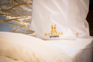 恩德培Hotel Horizon Entebbe的一张带白色枕头的床,上面有hilton标志