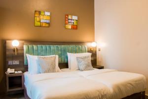 恩德培Hotel Horizon Entebbe的酒店客房设有两张床,墙上挂有两幅画作