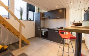 列日Le Studio Compostelle by Maison Brasseurs d'Etoiles的厨房配有黑色橱柜和红色凳子