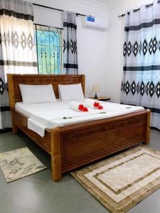 帕杰Tamu House Pajé Beach的一间卧室配有一张大木床,床上有红色的鲜花