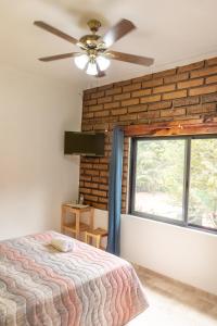 迪坡斯特兰CASA ANTARES的一间卧室设有砖墙、一张床和一个吊扇。