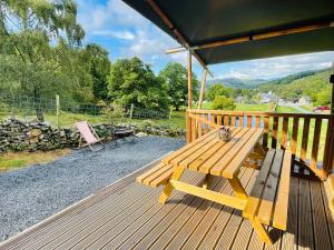 多尔盖罗Quirky Safari Tent with Hot Tub in Heart of Snowdonia的木甲板上设有长凳和桌子