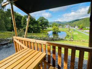 多尔盖罗Quirky Safari Tent with Hot Tub in Heart of Snowdonia的湖景门廊上的木凳