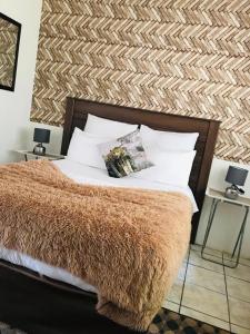 马盖特Dwengu Guest house的一间卧室配有一张带棕色毯子和枕头的床。