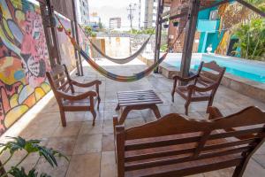 福塔莱萨Salve Maloca Hostel的庭院配有椅子、吊床和桌子