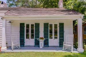 维克斯堡Steele Cottage的一个带绿色百叶窗和两把椅子的门廊