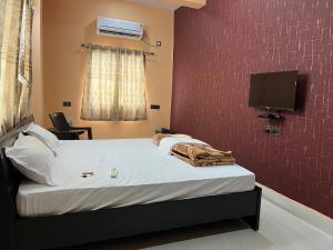 德奥加尔Hotel Krishna Paradise的卧室配有一张床铺,墙上配有电视