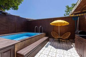 库鲁Villa Comfort-Soleil的一个带遮阳伞、桌子和椅子的游泳池