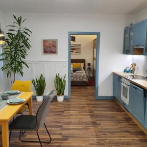 德布勒森Jégmadár Apartman的厨房以及带蓝色橱柜和桌子的用餐室。