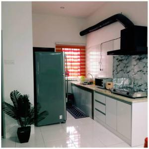 怡保Homestay Ibu(Muslim sahaja)的厨房配有绿色冰箱和盆栽植物