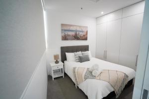 黄金海岸Air On Broadbeach-Stunning Ocean Views的白色卧室配有床和白色橱柜