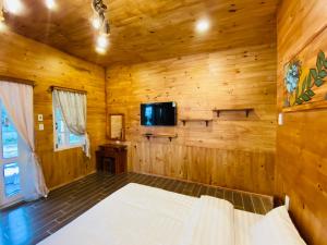 大叻贝瑞瓦利山林小屋的小木屋内的卧室配有1张床和电视