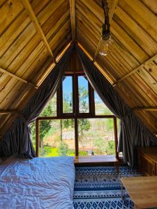 大叻贝瑞瓦利山林小屋的一张位于带大窗户的房间内的床铺