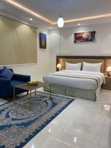 泰布克دانة الفخامه للشقق الخدومة的一间卧室配有一张大床和一张蓝色的沙发