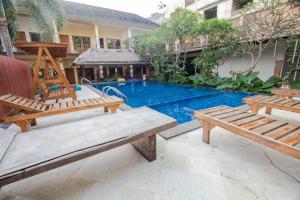 圣吉吉Central Inn Senggigi的两个木凳坐在游泳池旁
