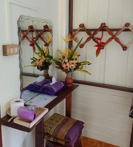 考索Khao Sok River & Jungle Resort的配有鲜花和镜子的桌子的房间