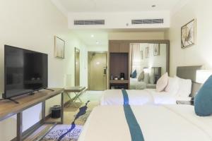 阿可贺巴Safwat Alkhobar Hotel的酒店客房设有两张床和一台平面电视。