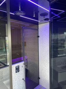 赞丹Above and Beyond - luxe suite met sauna en stoomdouche的玻璃门,建筑有紫色灯光