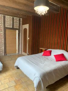 吕讷La Grange d Ave的卧室配有带红色枕头的大型白色床